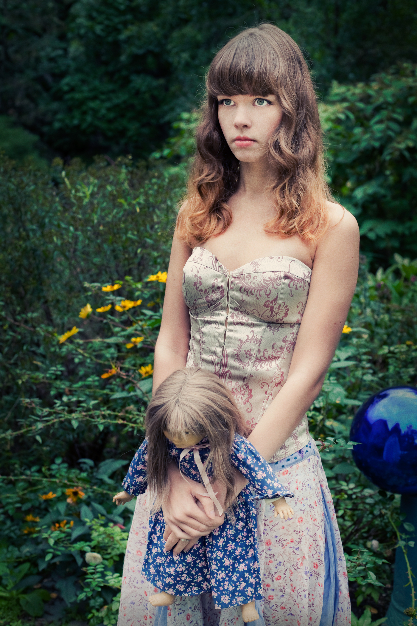 Girl poses as doll in garden. The Doll Collection by photographer Ella Sophie. Oakland CA