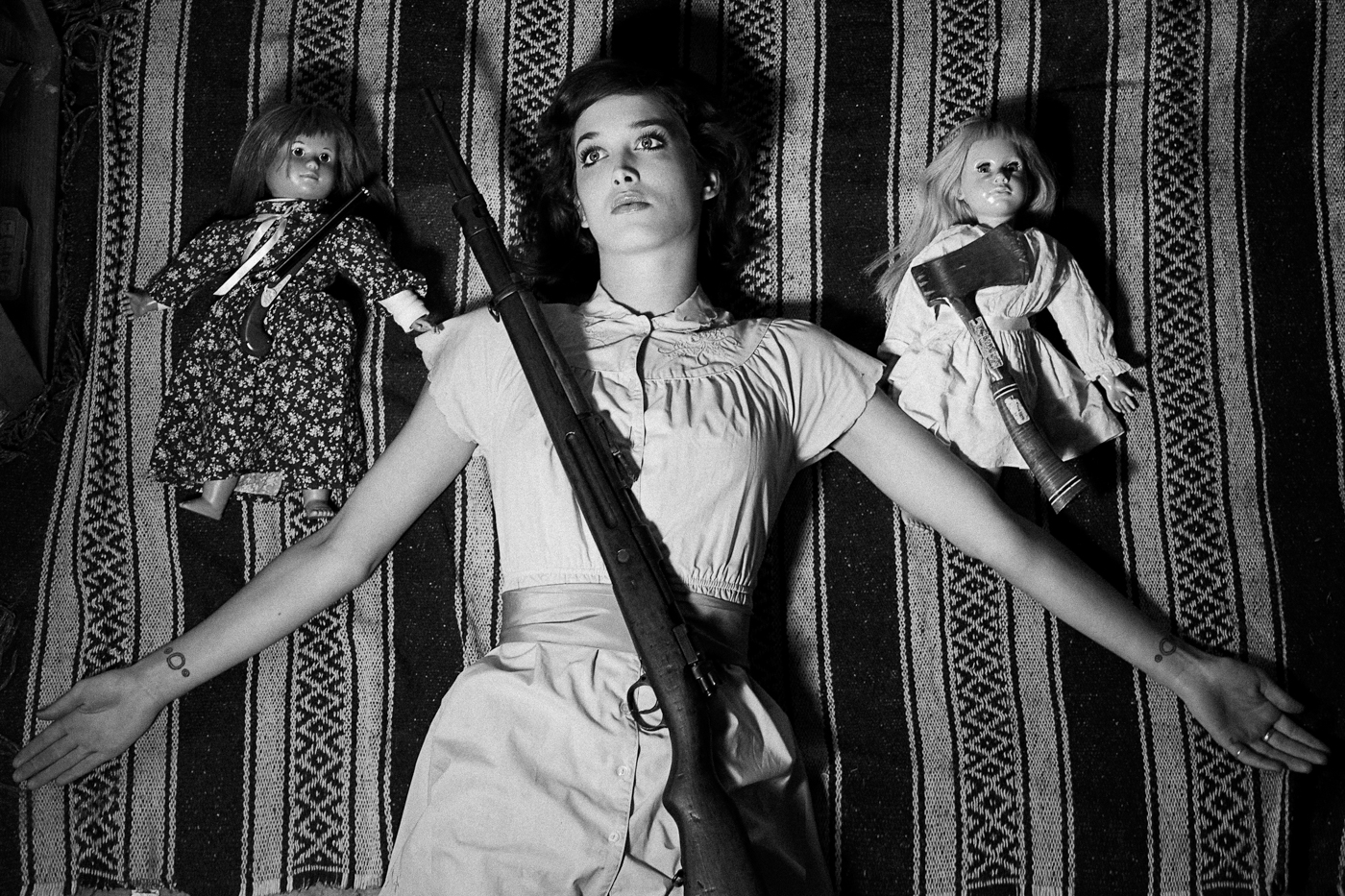 Acacia poses as doll with shotgun and armed dolls. Woodstock NY, artist Ella Sophie