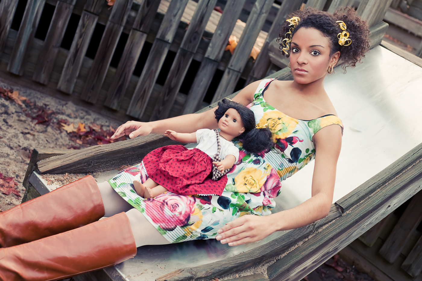 Model Lilith Mesidor poses as doll on slide in playground. Feminist photography by Ella Sophie