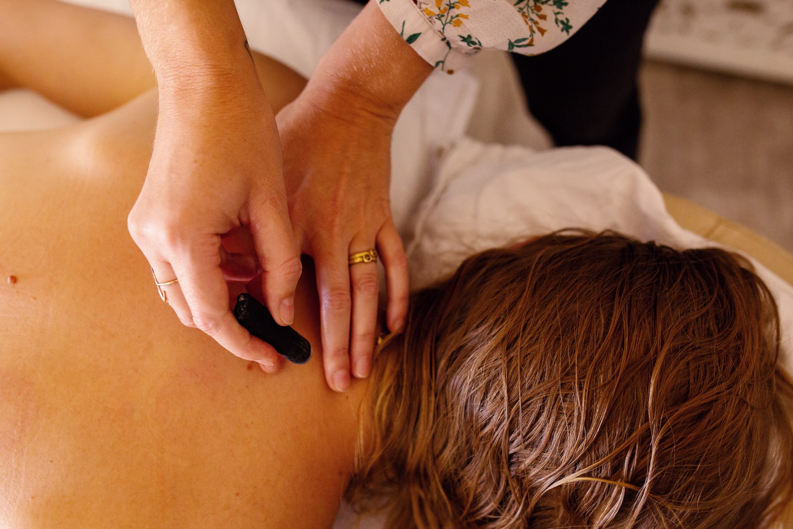 Business branding photography session for healthcare clinic, showing patient receiving treatment in clinic by healthcare professional. Close up shot of doctor's hands applying treatment on a woman's back. Photoshoot by Oakland photographer Ella Sophie.