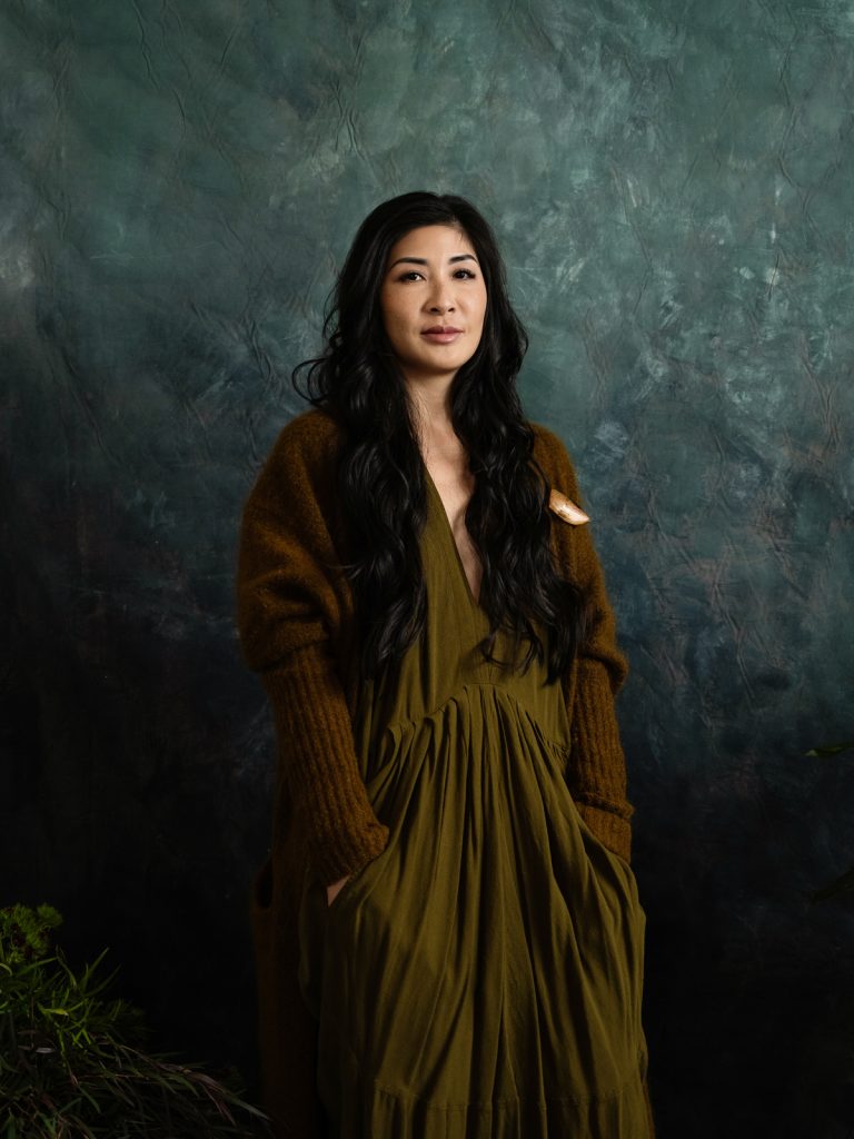 Creative portrait of asian woman in front of painted backdrop