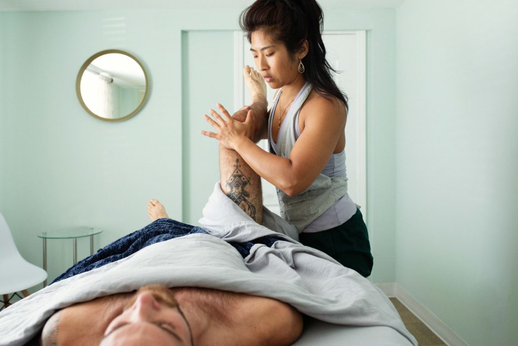Bodywork and massage therapist brand photography - showing massage therapist working with client's leg on a massage table. 